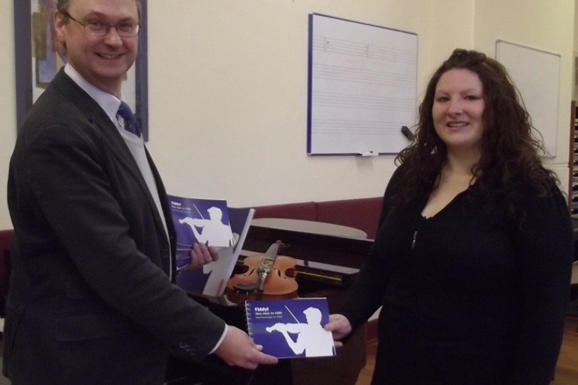 Laura Rowles presents copies of Fiddyl to Tom Field, violin teacher with the Department of Education and Children’s Music Service